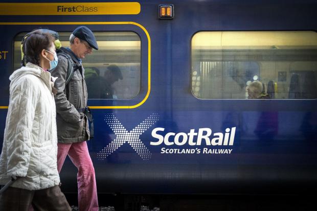 HeraldScotland: People walking past a ScotRail train