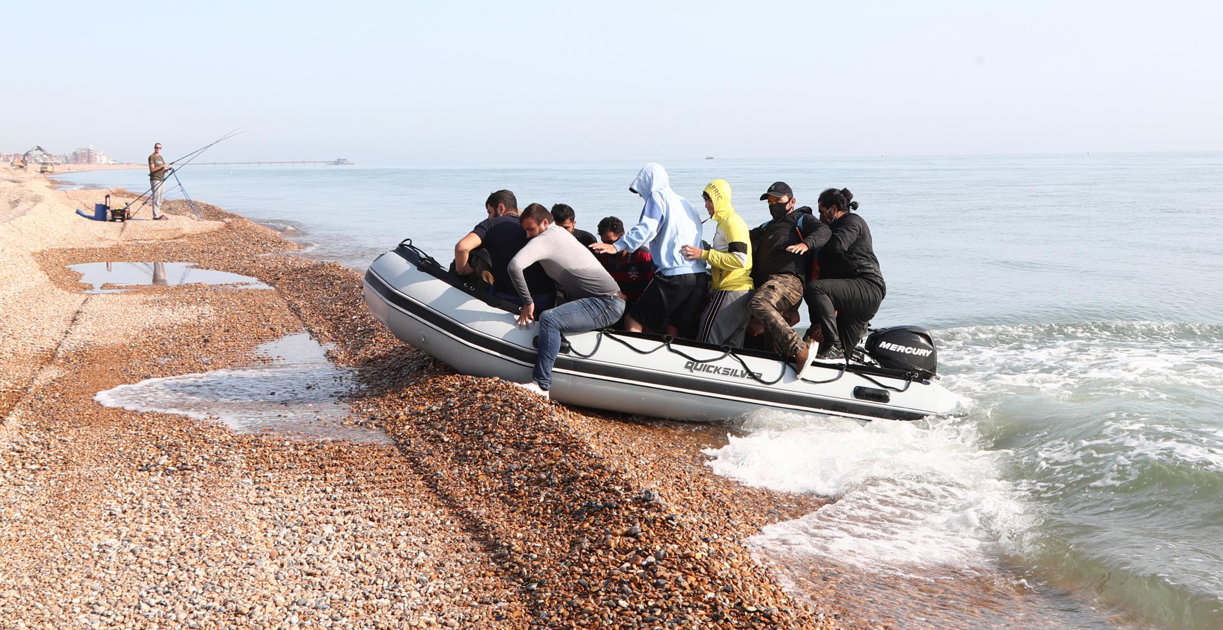 A group of people thought to be migrants arrive in an inflatable boat on a beach near Dover after crossing the Channel.
