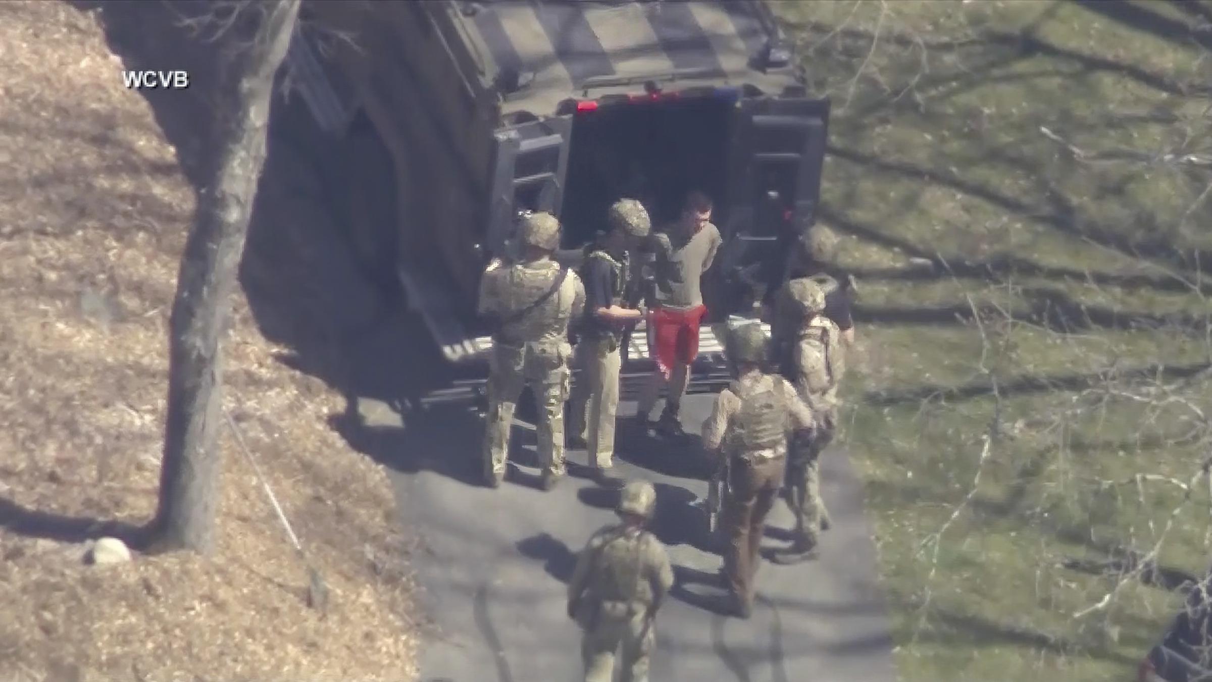 This image made from video provided by WCVB-TV, shows Jack Teixeira, in T-shirt and shorts, being taken into custody by armed tactical agents on Thursday, April 13, 2023, in Dighton, Mass. (WCVB-TV via AP).