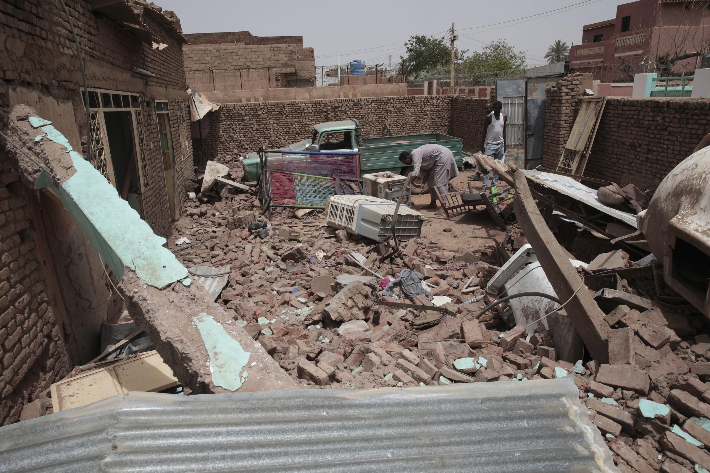 A man cleans debris of a house hit in recent fighting in Khartoum, Sudan, Tuesday, April 25, 2023. Sudans warring generals have pledged to observe a new three-day truce that was brokered by the United States and Saudi Arabia to try to pull Africas