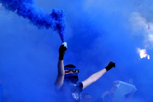 A Rangers fan holds up a smoke bomb at a game