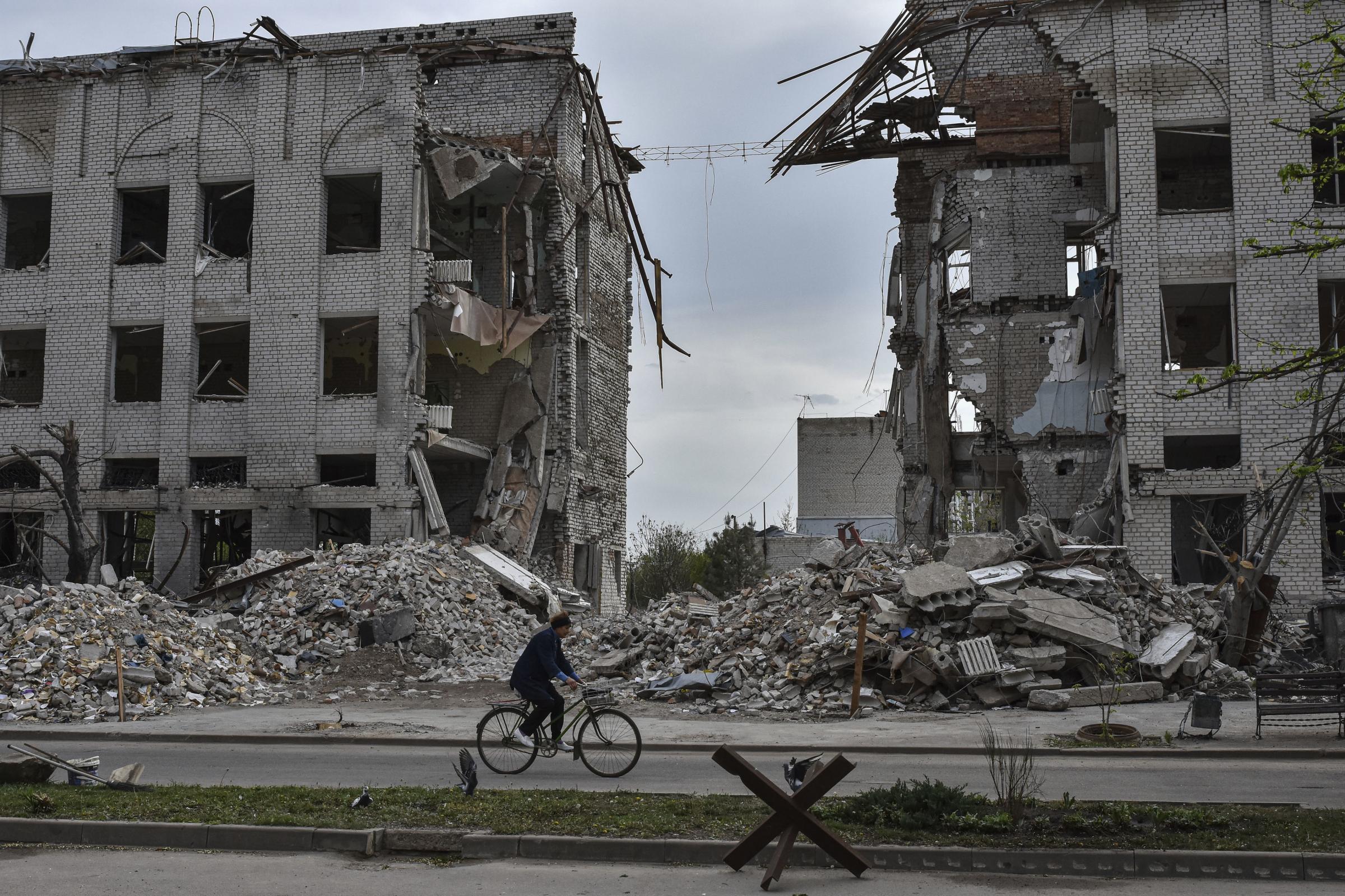 A local woman rides a bicycle in front of a building which was destroyed by a Russian airstrike in the frontline town of Orikhiv, Ukraine, on Thursday, April 18, 2024. (AP Photo/Andriy Andriyenko).