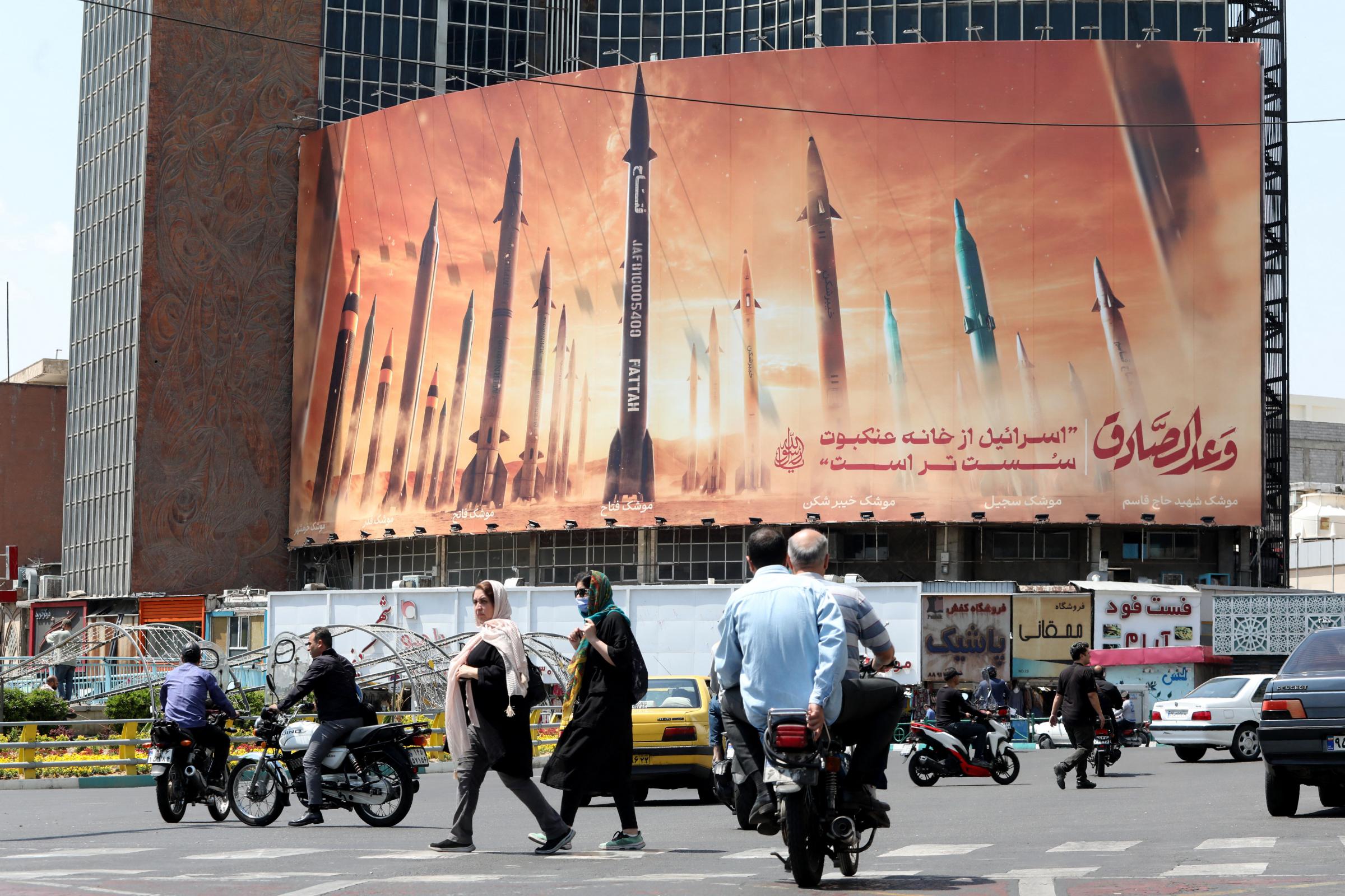 Motorists drive their vehicles past a billboard depicting Iranian missiles in Tehran on April 20, 2024, a day after Irans state media reported explosions in the central province of Isfahan. (Photo by ATTA KENARE / AFP) (Photo by ATTA KENARE/AFP via