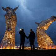 Roger Deacon and Pauline Stewart from Falkirk pictured at the Kelpies sculptures near Falkirk. The Kelpies, along with other prominent landmarks turned yellow this evening to remember the victims of the covid pandemic. Photograph by Colin Mearns.