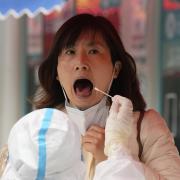 A woman opens her mouth for a swab during mass COVID tests on Friday, April 29, 2022, in Beijing. (AP Photo/Ng Han Guan).