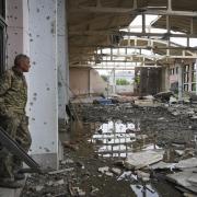 A Ukrainian serviceman looks at the ruins of the sports complex of the National Technical University in Kharkiv, Ukraine, Friday, June 24, 2022, damaged during a night shelling. The building received significant damage. A fire broke out in one part but
