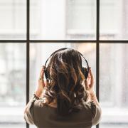 A woman listening to music on her headphoned. Credit: Canva