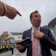 A protestor points at the BBC's Scotland correspondent James Cook