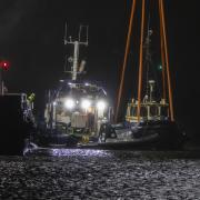 Salvage teams at Victoria Harbour recover a tugboat from the water in the Firth of Clyde near Greenock where two men died after it sank.