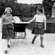 Prince Charles, 11, and Princess Anne, 10, pull the pram of their baby brother, Andrew, around the grounds of Balmoral in September 1960
