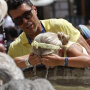 A child refreshes herself at a fountain in downtown Rome (AP Photo/Riccardo De Luca).