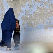 A burqa-clad woman walks with a girl along a street in Kabul
