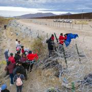 Migrants place clothing atop razor wire  to cross the border into El Paso, Texas from Ciudad Juarez, Mexico.
