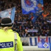A police officer keeps an eye on football fans at a Scottish match