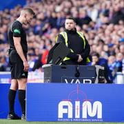 Referee David Dickinson looks at the pitchside monitor at Ibrox today