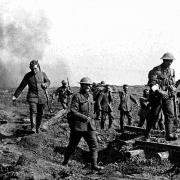 German prisoners help carry wounded British soldiers back to trenches during Battle of Somme