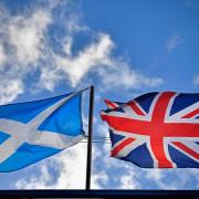 A saltire flag and Union Jack flutter in the wind on in Glasgow. (Photo by Jeff J Mitchell/Getty Images).