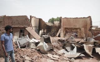 A man walks past a destroyed home in Khartoum