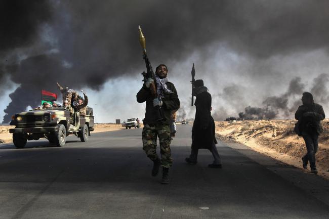 RAS LANUF, LIBYA - MARCH 11:  Libyan rebels battle government troops as smoke from a damaged oil facility darkens the frontline sky on March 11, 2011 in Ras Lanuf, Libya. Government troops loyal to Libyan leader Muammar Gaddafi drove opposition forces out